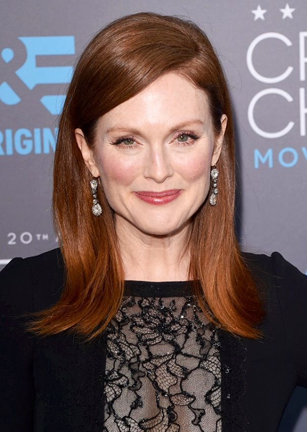 Retrato de uma mulher com cabelo ruivo escuro e liso, sorrindo. A cor exemplifica uma opção elegante para mulheres maduras.