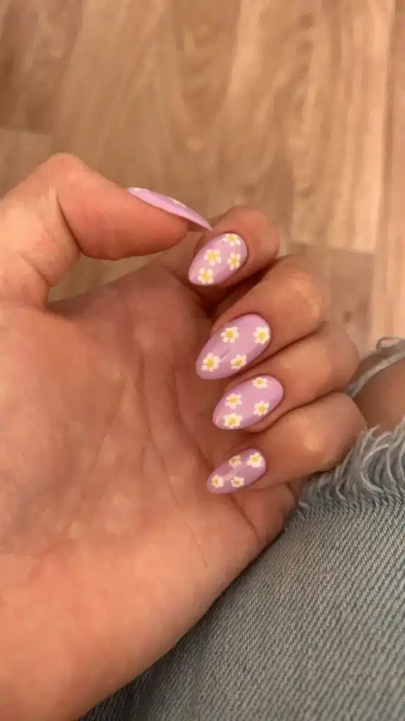Unhas decoradas com esmalte rosa e detalhes florais.
