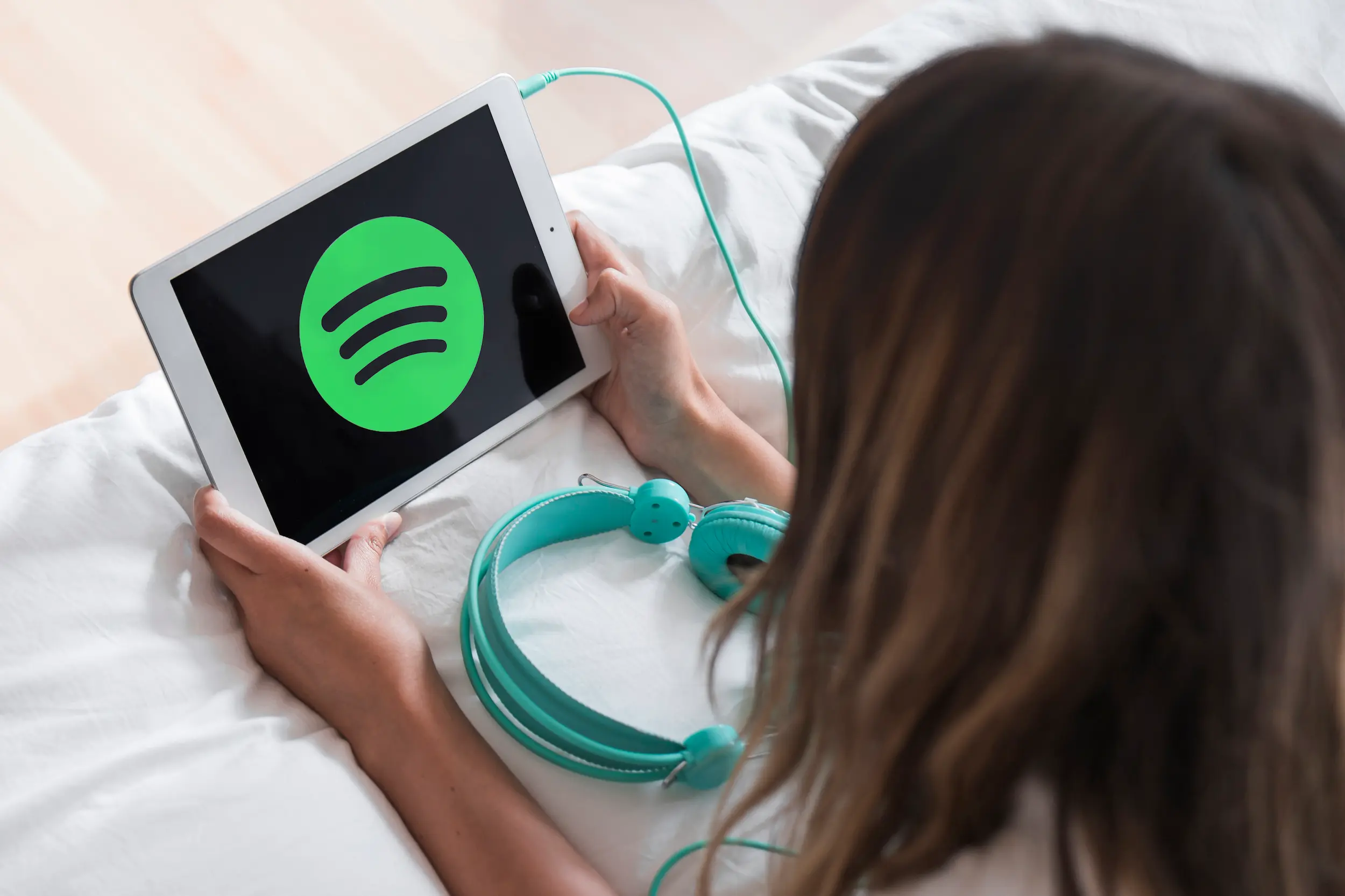 Imagem mostrando logo do Spotify em tablet, com fones de ouvido, ilustrando as novidades para usuários gratuitos.