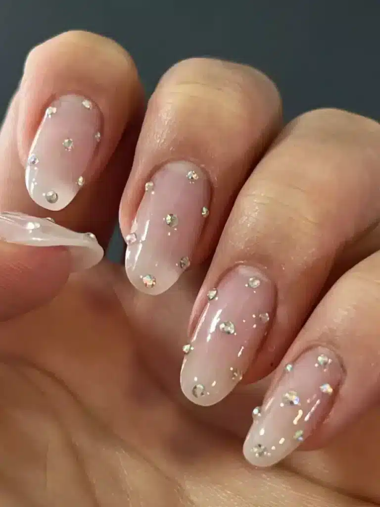 Unhas delicadas com strass brilhantes, destacando a versatilidade e a praticidade de designs minimalistas.