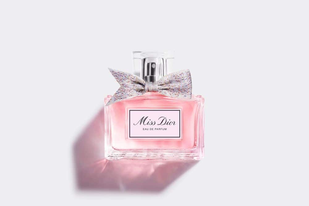 Frasco do perfume Miss Dior Eau de Parfum, na cor rosa suave com um laço delicado, representando a elegância das fragrâncias florais para a primavera.