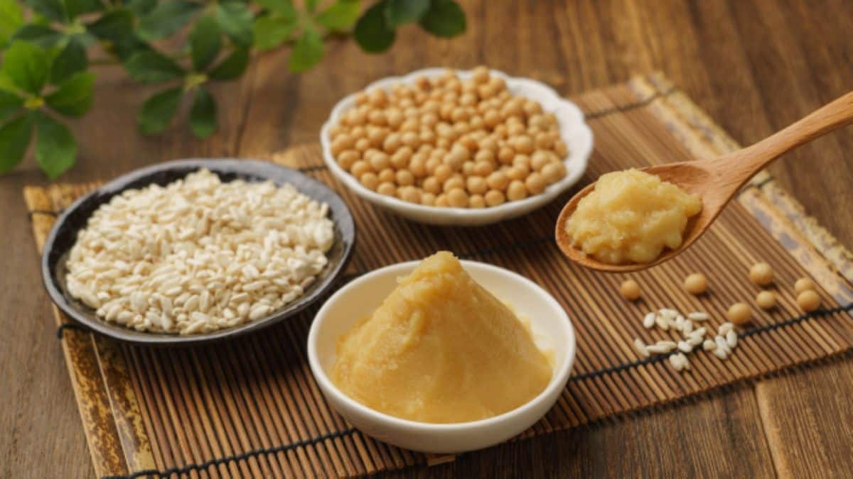 Ingredientes e pasta de Missô em tigelas: pasta amarela cremosa de missô, grãos de soja e arroz koji (arroz fermentado), ilustrando a base da culinária japonesa.