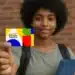 Jovem segurando cartão colorido do Programa Bolsa Família com sorriso leve