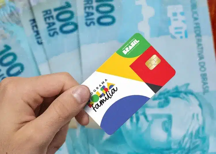 Cartão do Bolsa Família com cédulas de 100 reais ao fundo, tema Governo finaliza pagamentos.