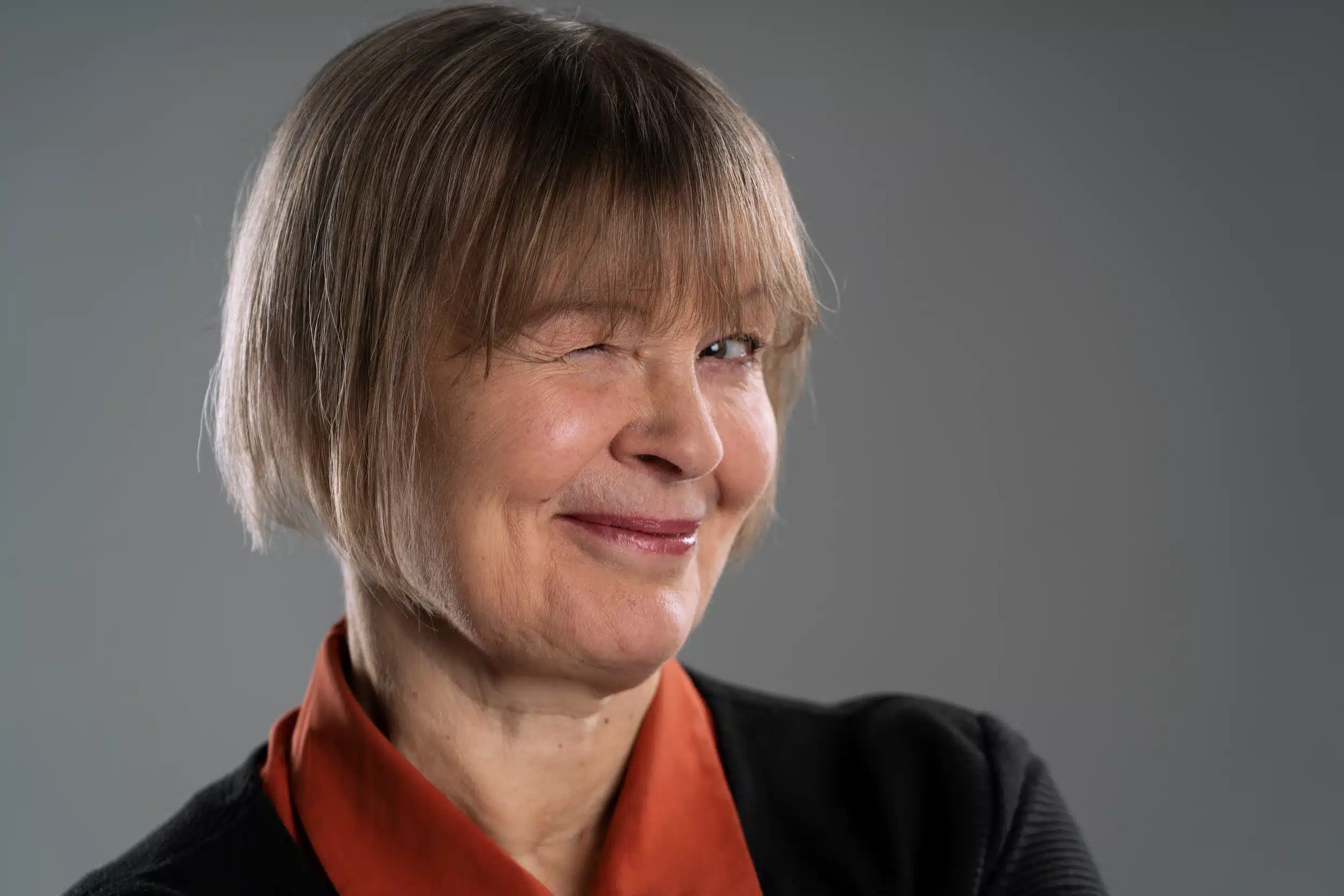 Mulher sorrindo e piscando, com cabelo curto e franja, representando a tendência do corte de cabelo para mulheres 50+.