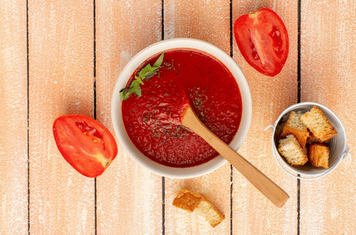 Molho de tomate caseiro em uma tigela, temperado e pronto, com fatias de tomate e croutons ao redor, mostrando o resultado da receita com ingredientes frescos.