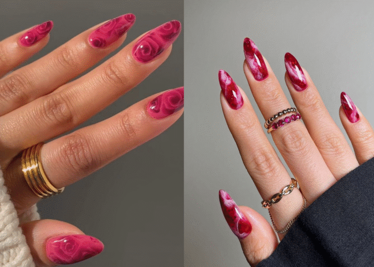 Duas mãos com unhas stiletto alongadas em tons de rosa e vermelho, apresentando a nail art em efeito mármore e rosas.