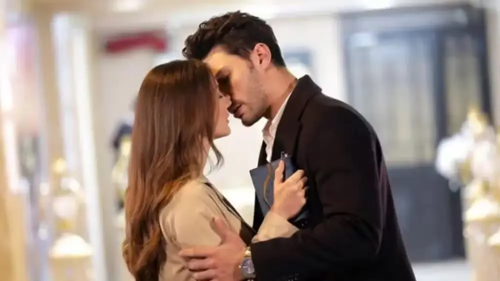 Casal em cena romântica de Esqueça-me Se Puder, com um beijo no ambiente de comédia e drama.