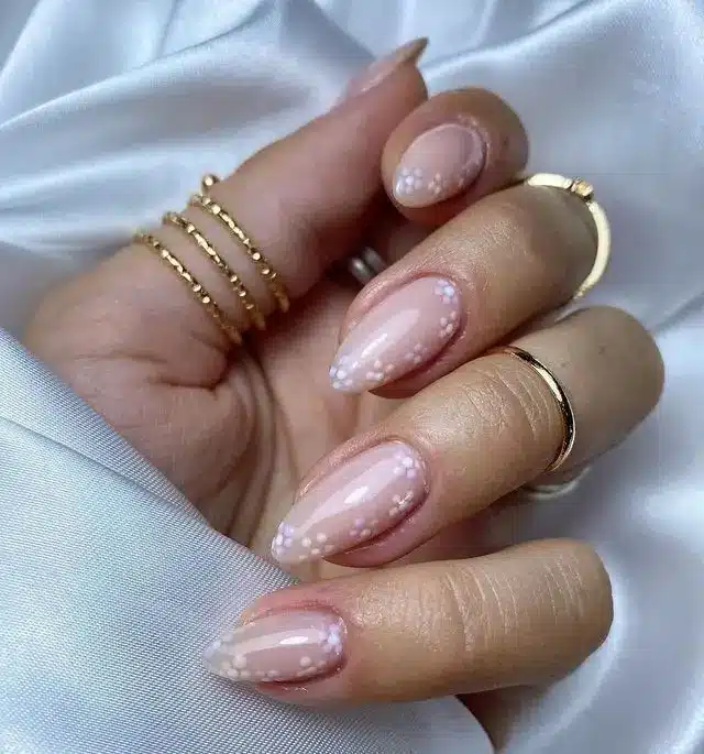 Nail art minimalista com flores delicadas no canto das unhas.