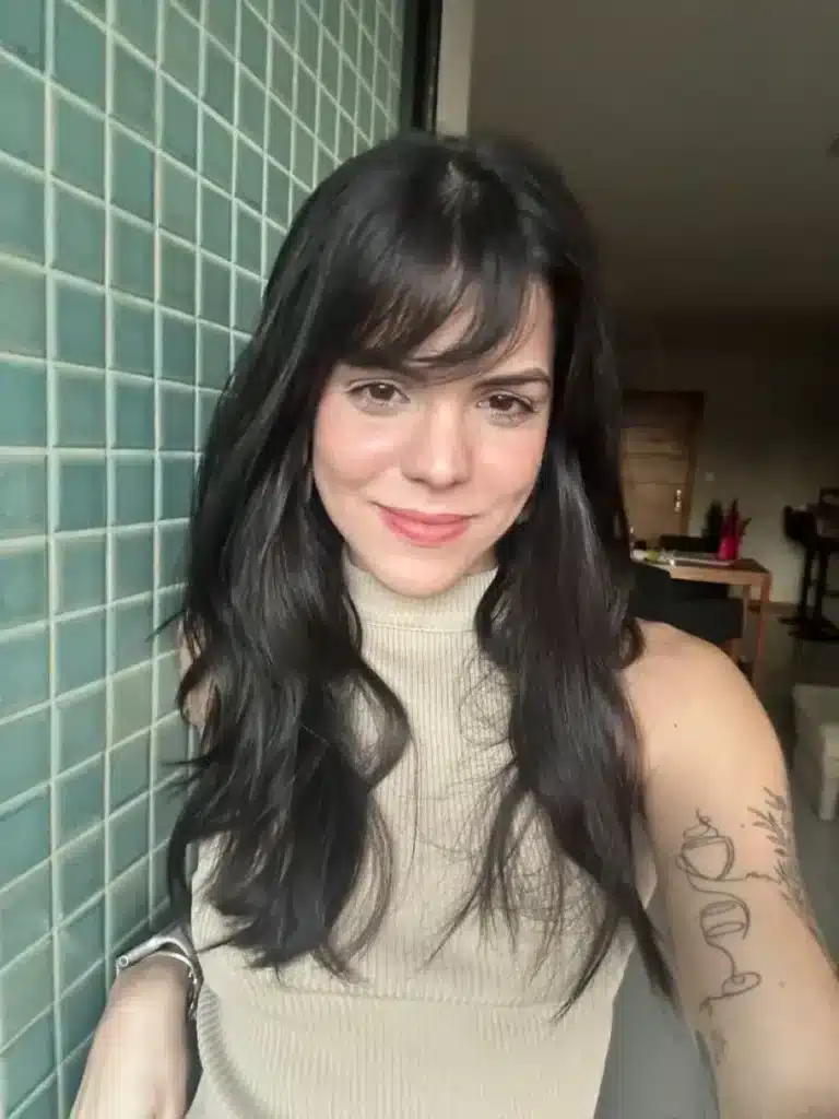 Mulher com franja borboleta, mostrando o movimento e leveza no estilo de cabelo.