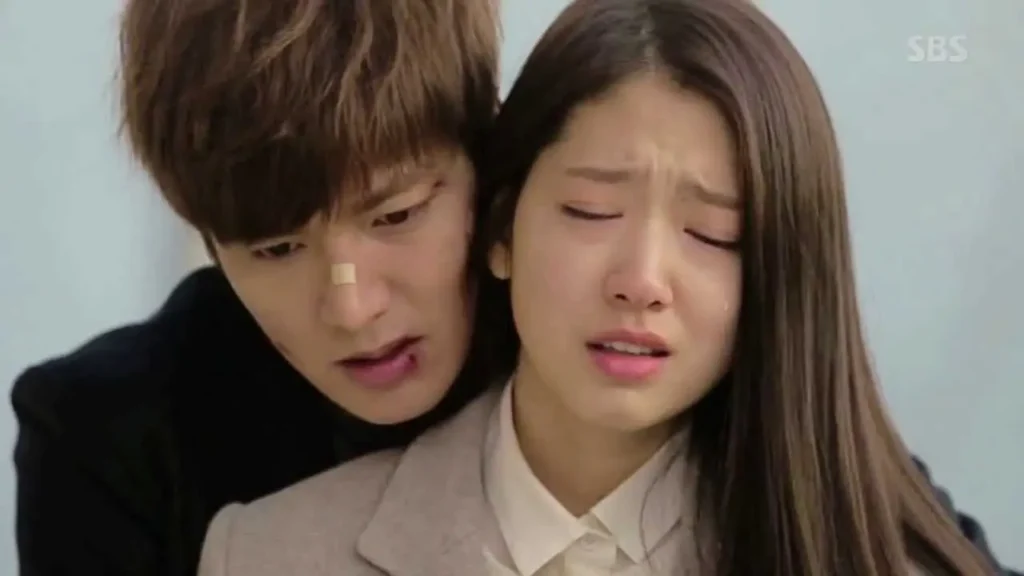 Cena de 'Os Herdeiros' com Kim Tan (Lee Min Ho) confortando Cha Eun Sang (Park Shin Hye), ambos em um momento de tensão emocional.