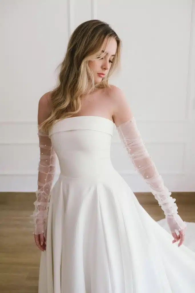 Mulher usando vestido branco elegante com luvas transparentes longas, estilo opera glove.