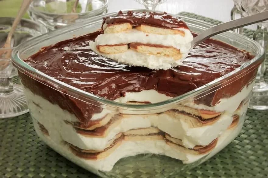 Mousse de Leite Ninho com Chocolate e biscoitos intercalados, cobertos com ganache de chocolate cremoso.