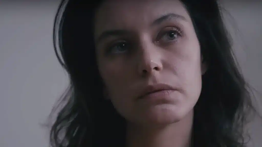 Mulher com expressão pensativa, cena da série O Segredo do Templo.