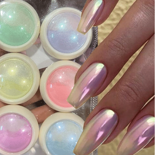 Mãos com unhas longas em formato stiletto decoradas com pó cromado perolado, com potes de pó colorido ao fundo