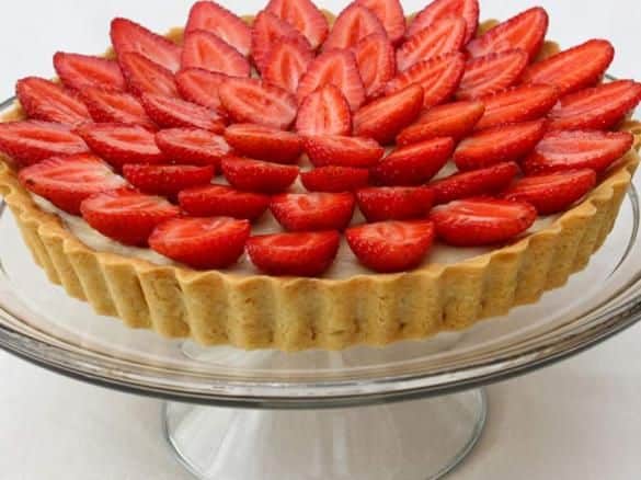 Torta de morango decorada com fatias de morangos frescos em forma de leque, destacando uma receita de sobremesa.