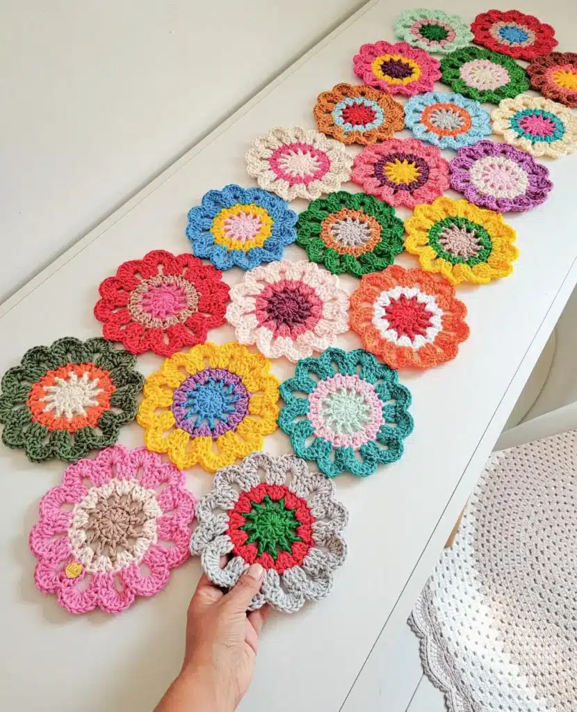 Trilho de crochê com flores coloridas e delicadas, feitas em pontos altos, com destaque para as diferentes cores das pétalas e o formato das flores.