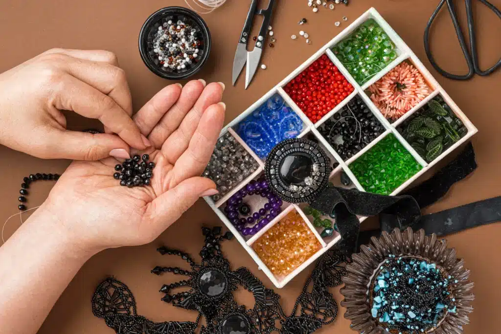 Pessoa montando bijuterias personalizadas com miçangas e outros itens de artesanato.