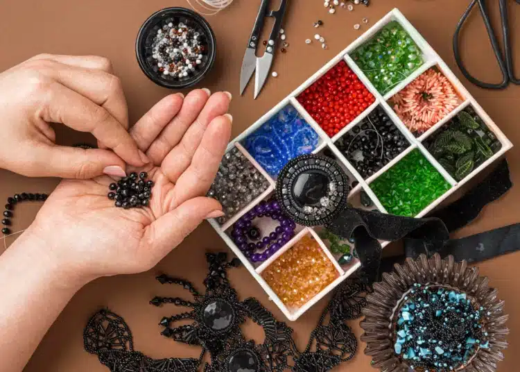 Pessoa montando bijuterias personalizadas com miçangas e outros itens de artesanato.