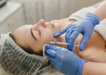 Profissional aplicando botox no rosto de uma mulher durante procedimento estético.