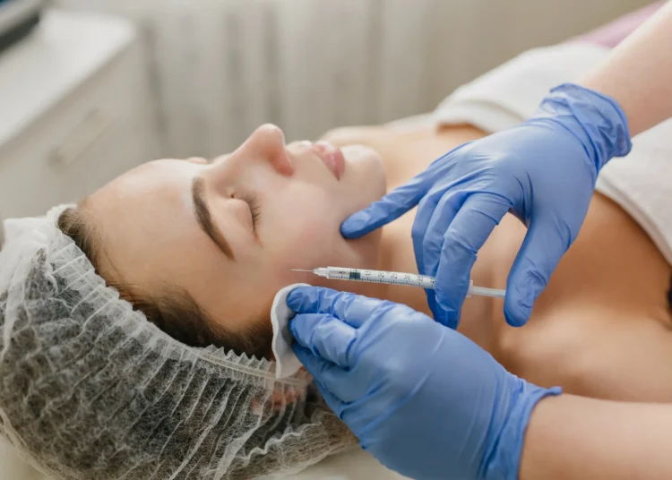 Profissional aplicando botox no rosto de uma mulher durante procedimento estético.
