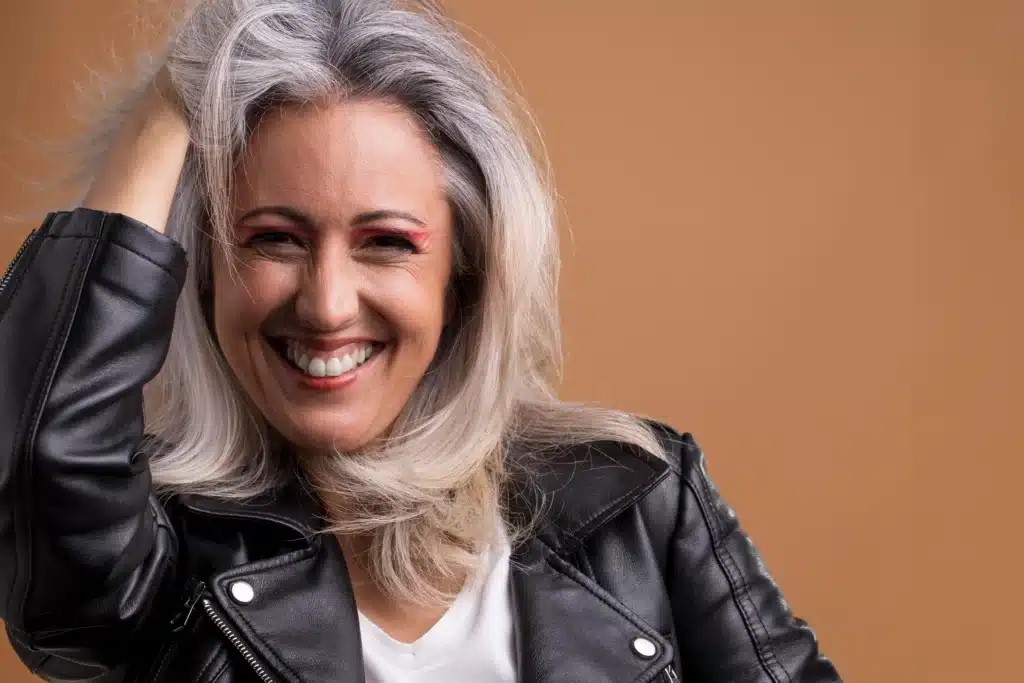 Mulher sorrindo com cabelos brancos e platinados.