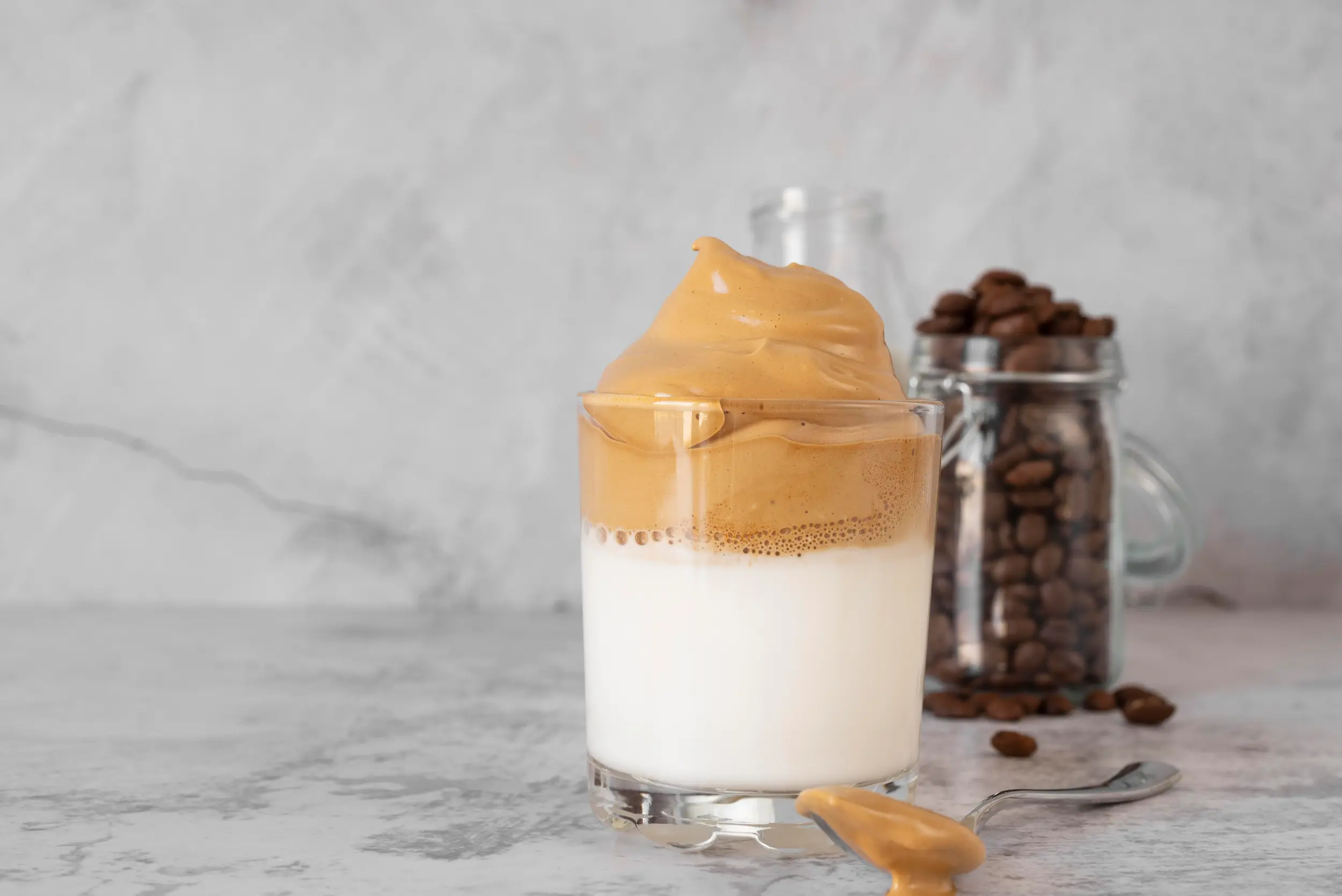"Imagem de café cremoso com canela, servido em um copo com leite, destacando a camada cremosa de café por cima.