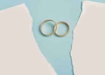 Anéis de casamento sobre papel rasgado, simbolizando o impacto de mudanças na partilha após a morte durante um divórcio.