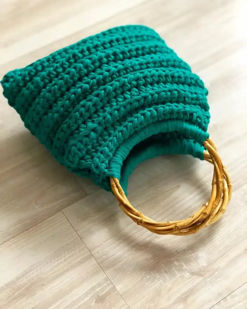 Bolsa de crochê com alça de bambu circular verde, ilustrando o estilo orgânico e moderno das alças de bambu.