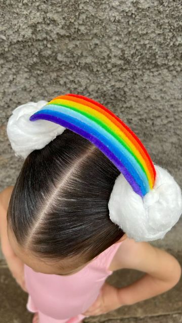 Menina com penteado criativo de cabelo maluco com tiara de arco-íris e nuvens brancas, ideal para festa temática ou dia do cabelo maluco na escola.