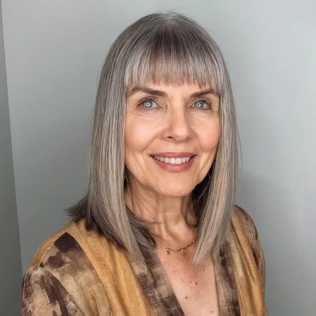 Mulher com cabelo grisalho e franja reta curta, sorrindo.