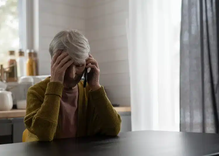 Idosa preocupada falando ao telefone, representando risco de golpe digital.