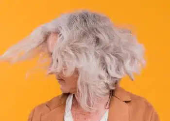 Mulher com cabelo grisalho e volumoso, mostrando movimento com o vento.