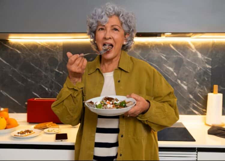 Idosa aproveitando refeição saudável em casa, representando bons hábitos alimentares após os 60 anos