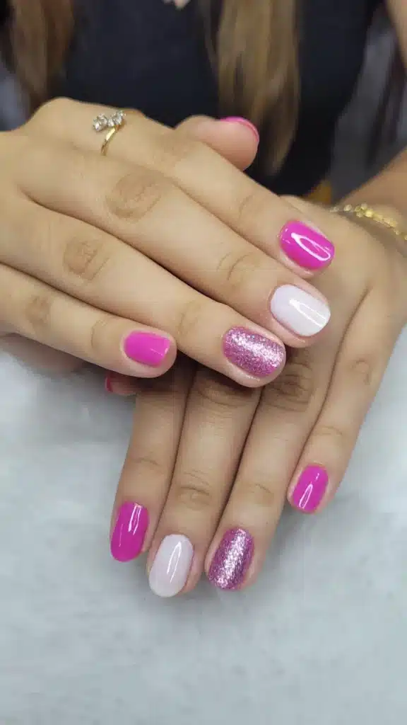 Unhas decoradas com glitter delicado, combinando rosa cremoso e glitter prateado no dedo anelar.