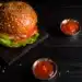 Deliciosa foto de um hambúrguer com molho, queijo, alface e ketchup, acompanhado de batatas fritas, representando o tempero secreto do Outback.