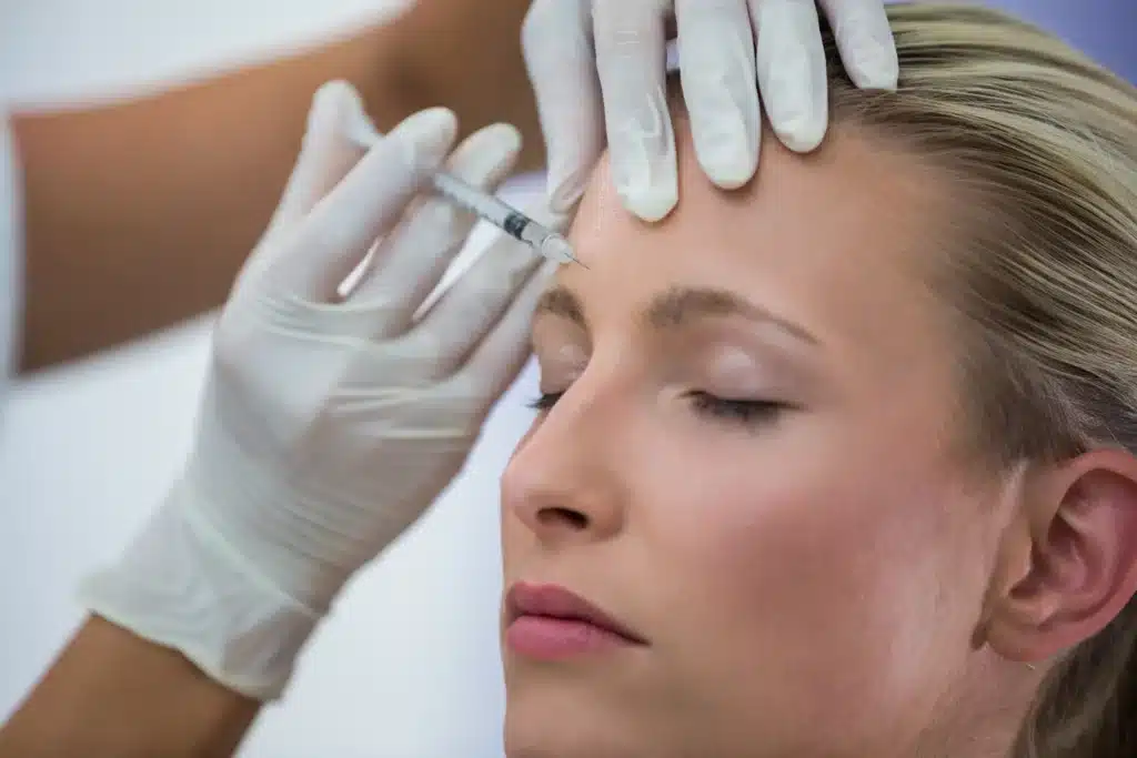Profissional aplicando botox na testa de uma paciente em um procedimento estético.