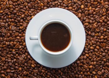 Xícara de café espresso em cima de grãos de café torrados em fundo escuro