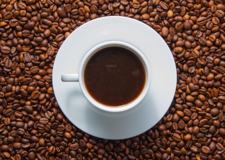 Xícara de café espresso em cima de grãos de café torrados em fundo escuro