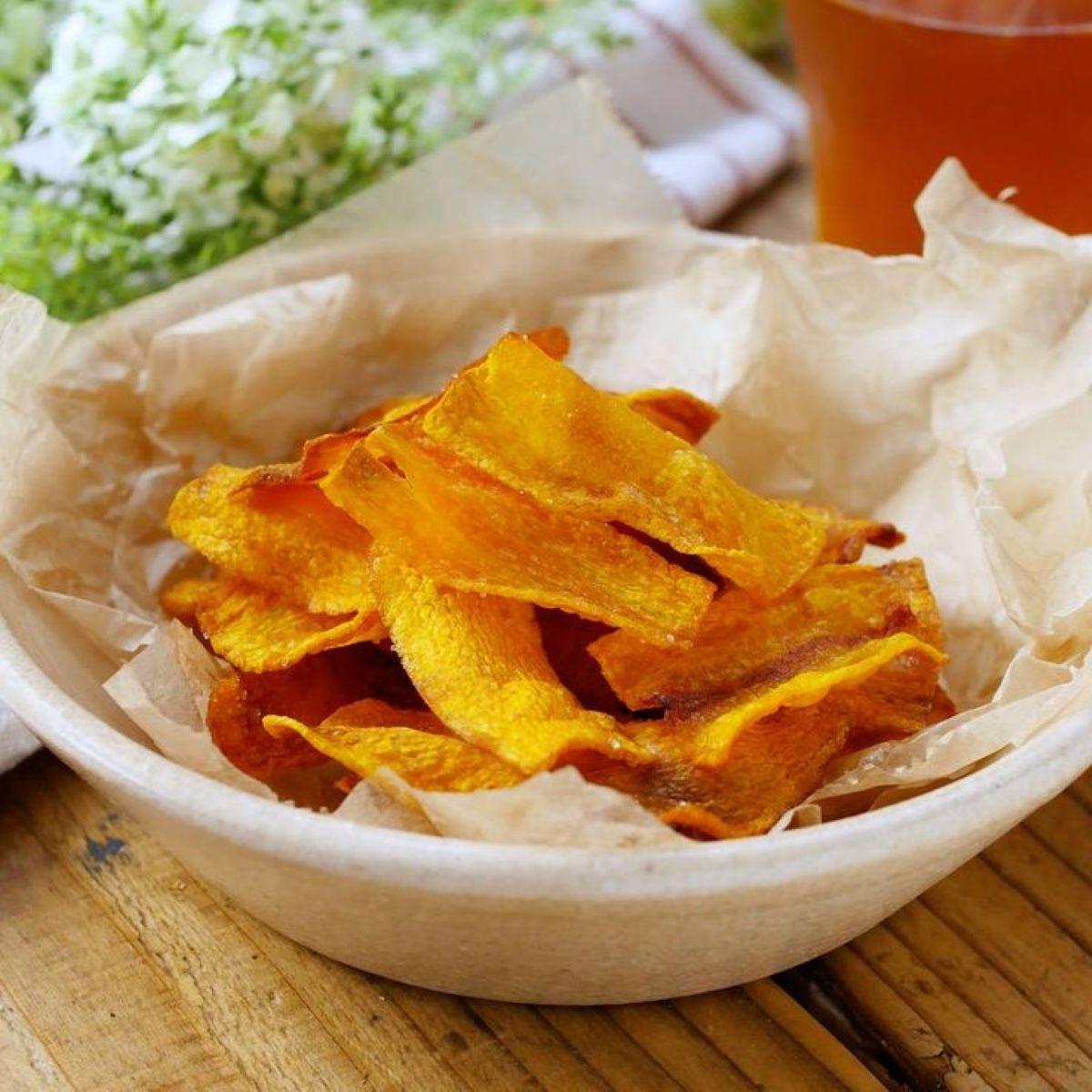 Chips crocantes de cenoura (ou batata-doce) em uma tigela, um exemplo de petisco delicioso e simples feito a partir do reaproveitamento criativo de sobras de vegetais.