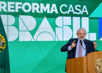 O Presidente da República, Lula, em um discurso oficial, apontando para o painel de fundo com a inscrição "REFORMA CASA BRASIL". A imagem marca o lançamento deste novo programa de habitação e melhoria residencial do governo.