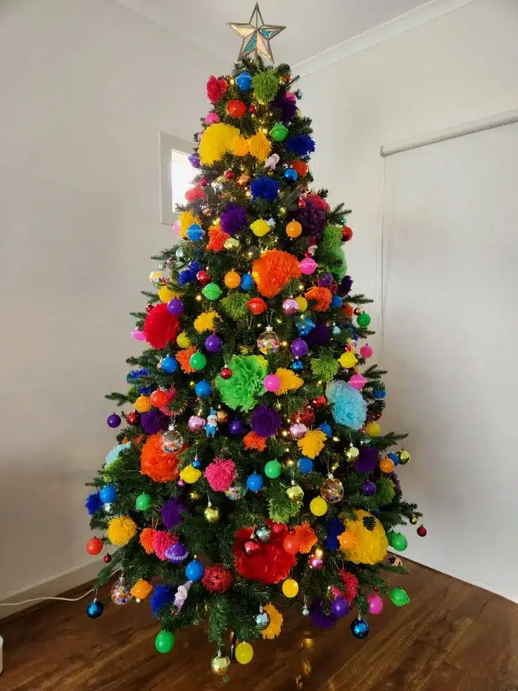 Árvore de Natal colorida com bolas e pompons vibrantes, criando uma decoração única e cheia de personalidade.