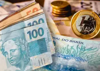Cédulas e moedas de reais representando benefício mensal de R$ 600 para idosos no Brasil.