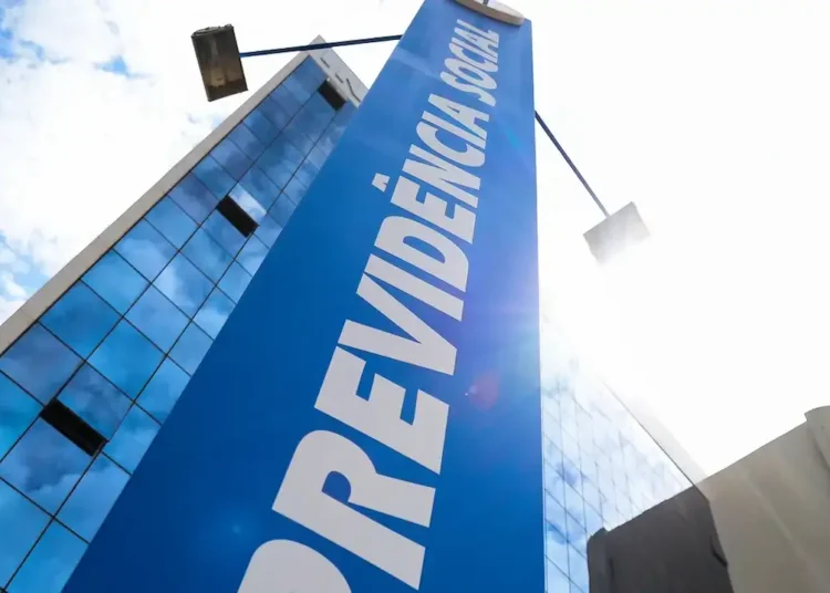 Fachada de prédio do INSS com placa azul sob céu claro.