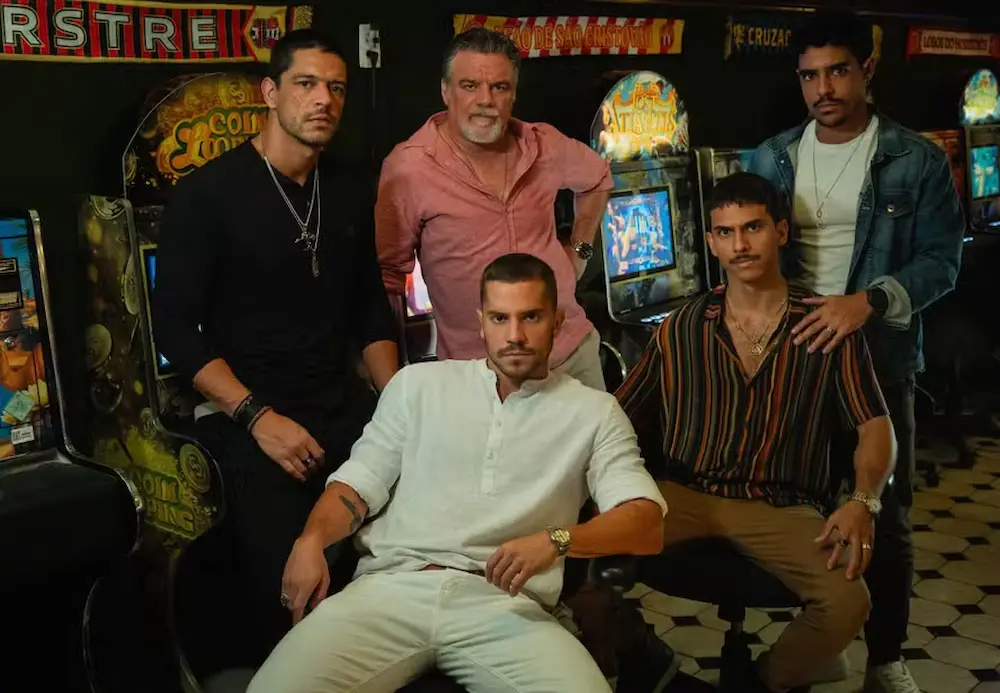 Membros da Família Moraes de 'Os Donos do Jogo', nova série da Netflix, posando em frente a máquinas de fliperama."