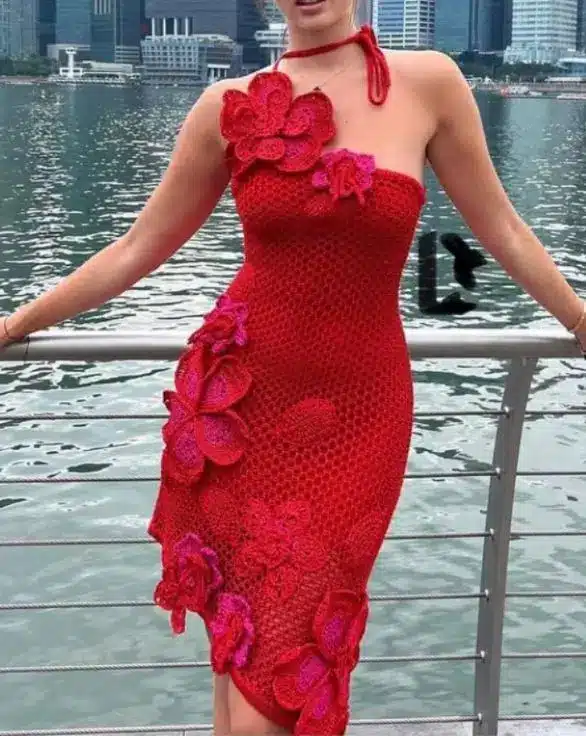 Mulher usando vestido de crochê vermelho com flores em relevo 3D.