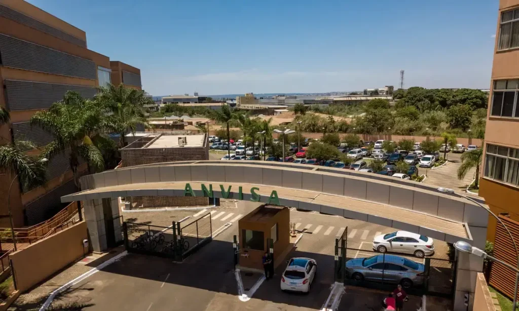 Vista aérea da entrada da sede da Anvisa, com o letreiro 'ANVISA'.