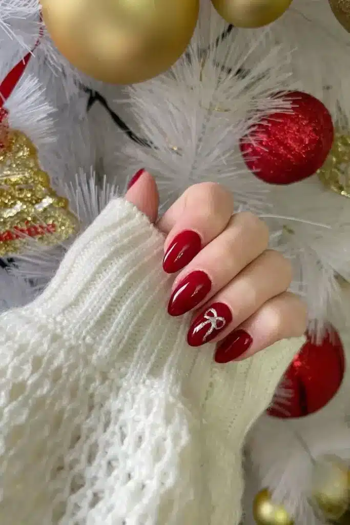 Unhas Natalinas com Laços Delicados Unhas vermelhas com laços delicados de fita prateada, ideal para o Natal.