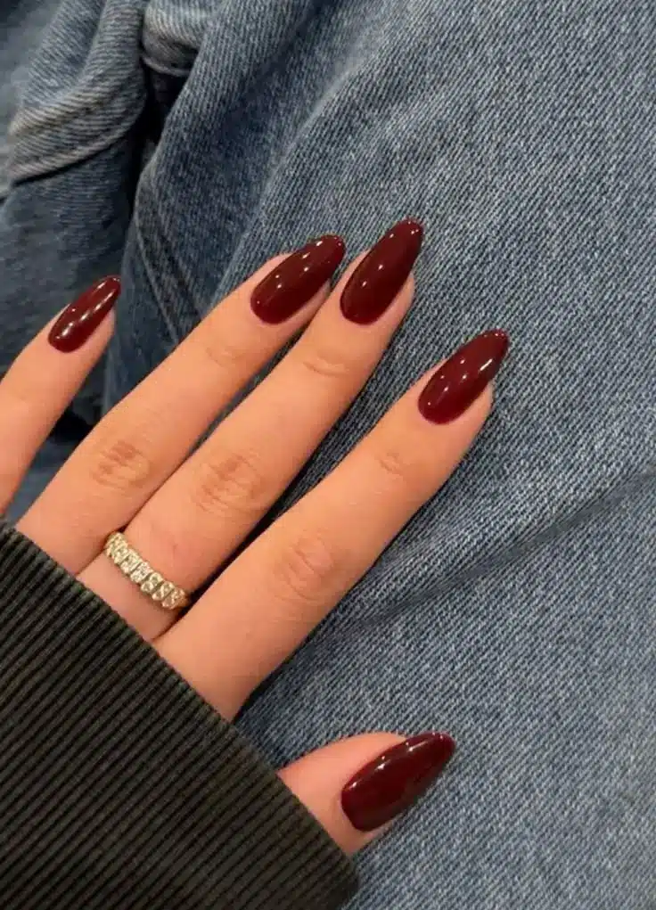 Vermelho cereja Unhas vermelhas cereja em formato amendoado com anel de diamantes visível.
