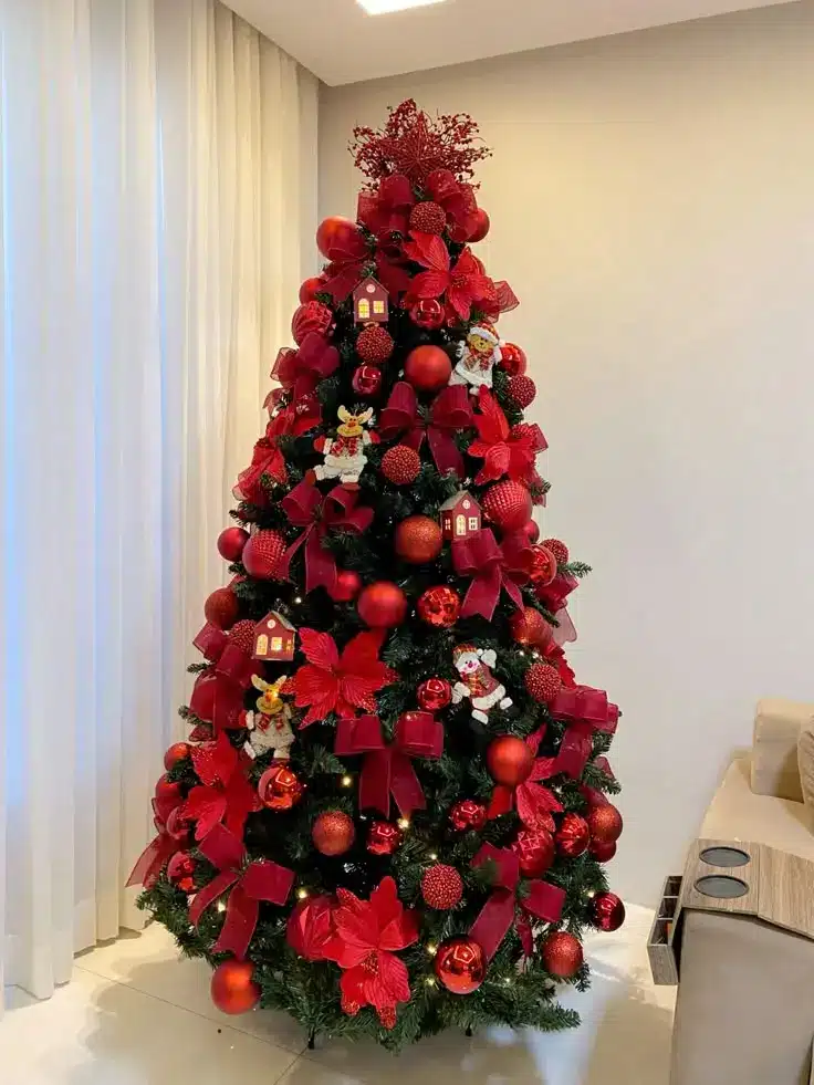 Árvore de Natal decorada com laços vermelhos, flores artificiais e detalhes natalinos, criando um visual elegante e vibrante.
